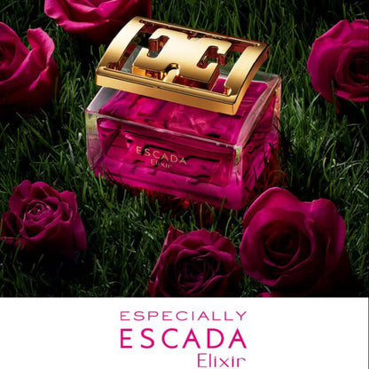 Escada perfume bottle with gold cap surrounded by pink roses on grass