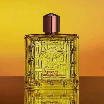 Versace Eros Energie perfume bottle on a gradient yellow and orange background