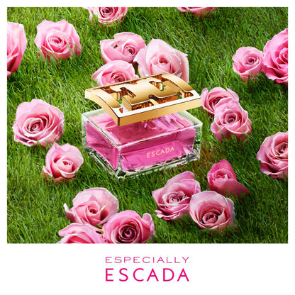 Escada perfume bottle surrounded by pink roses on grass